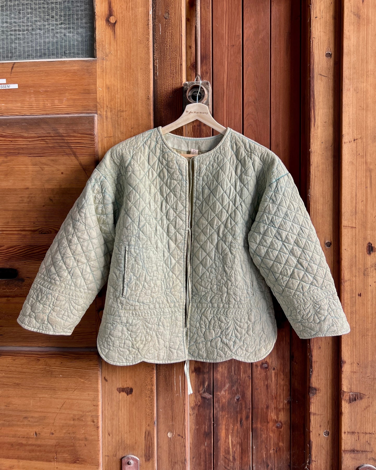 Green quilted jacket hanging on a wooden door