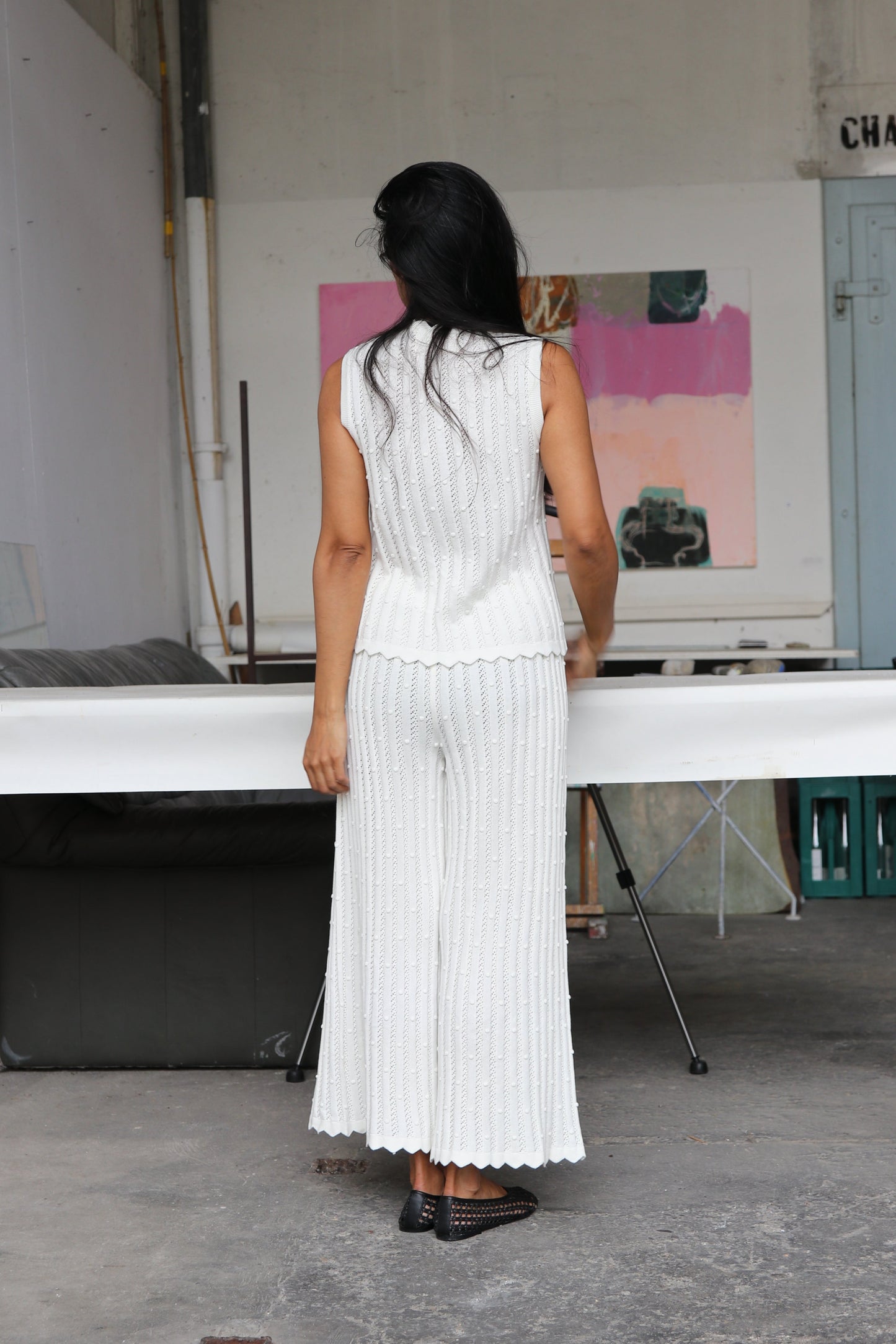Woman wearing a white knitted outfit standing in an artist's workshop