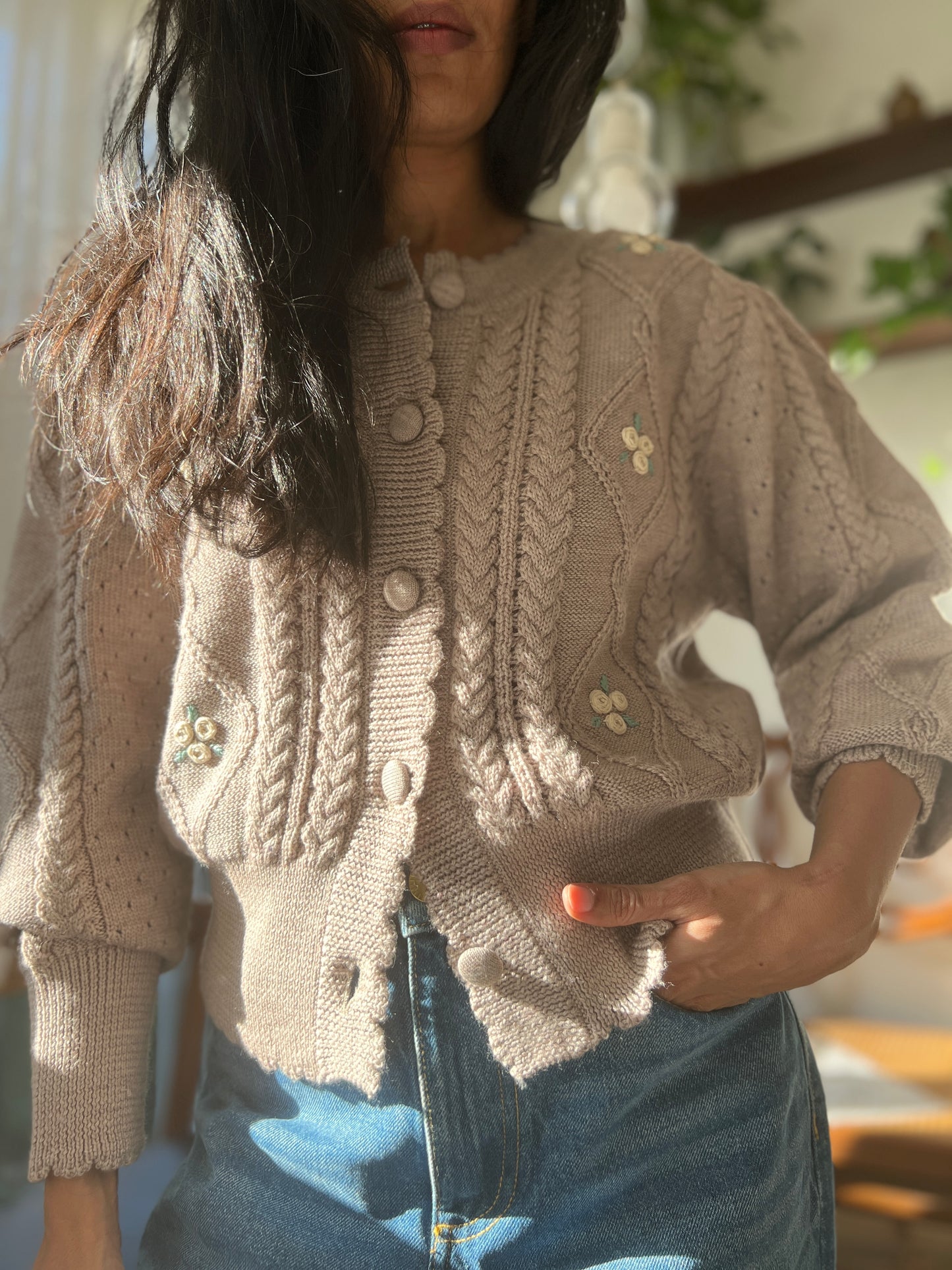 Model wearing Sienna Cardigan made from organic merino wool, featuring knitted cables, puff sleeves, and embroidered flowers.