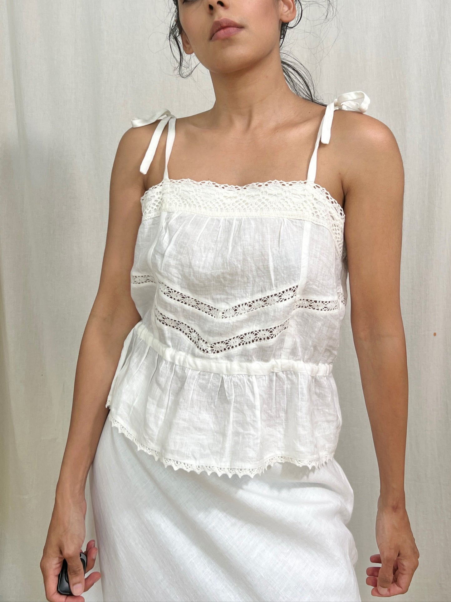 Woman wearing a white lace top against a plain background