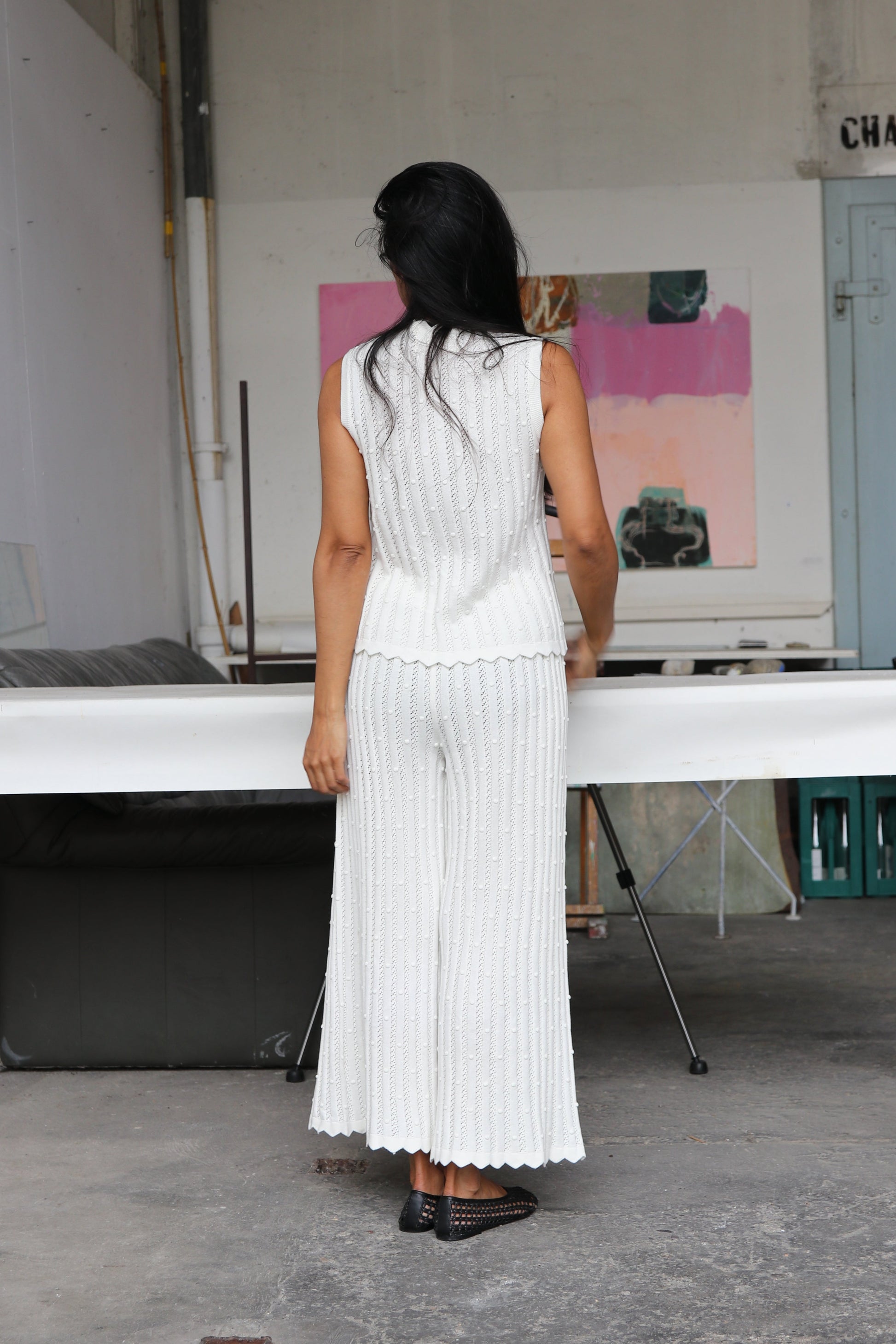 Woman wearing a white knitted outfit standing in an artist's workshop