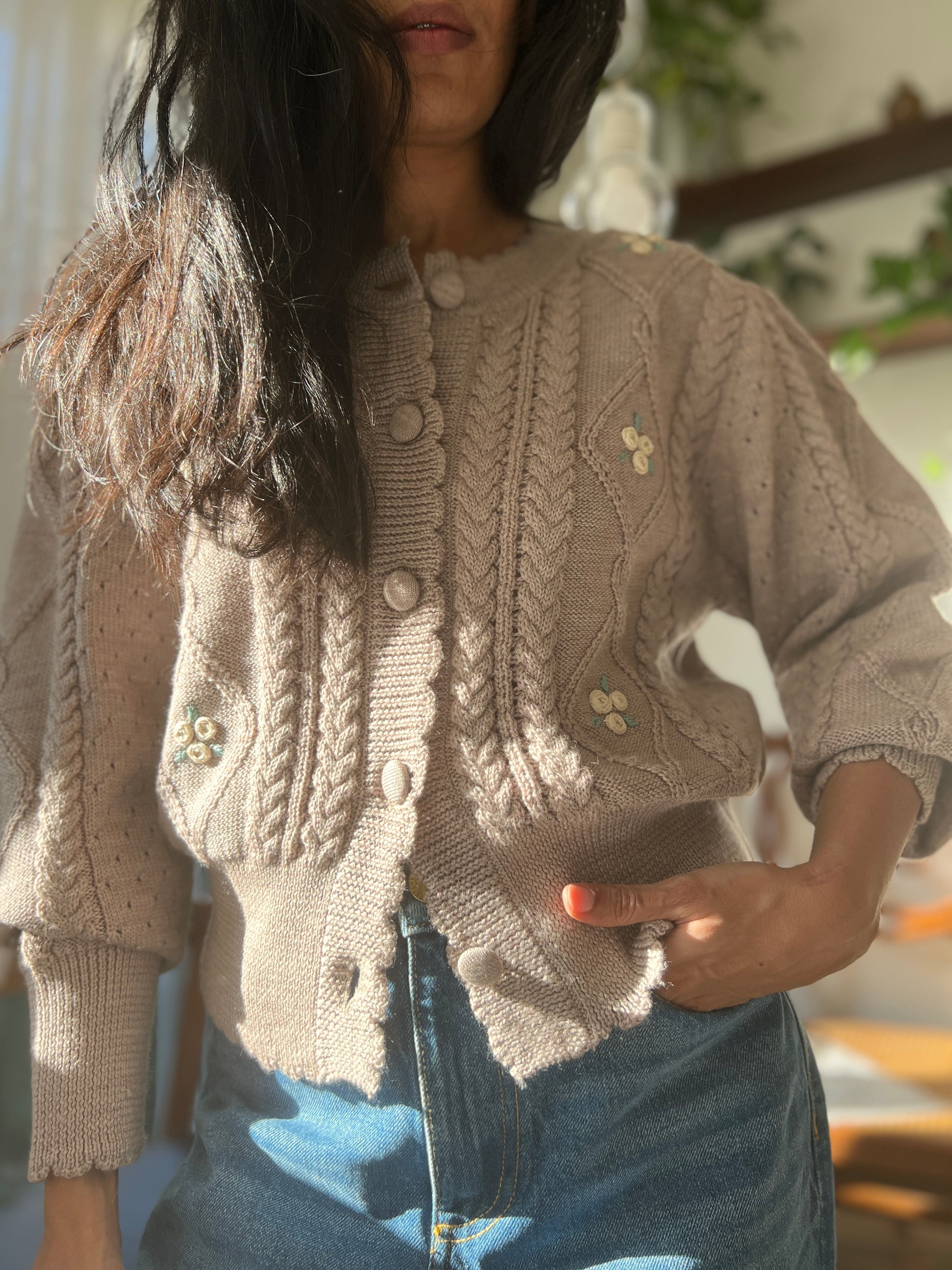 Model wearing Sienna Cardigan made from organic merino wool, featuring knitted cables, puff sleeves, and embroidered flowers.